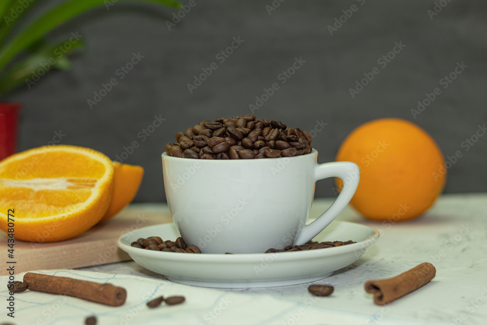 White coffee cup with coffee beans and cinnamon sticks White coffee cup with coffee beans and cinnamon sticks