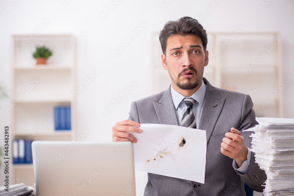 Young male employee unhappy with excessive work in the office Young male employee unhappy with excessive work in the office