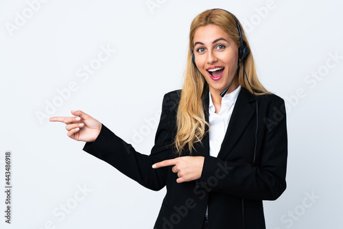 Young telemarketer woman over isolated white background surprised and pointing side