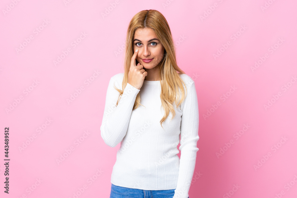 Young Uruguayan blonde woman over isolated pink background showing something Young Uruguayan blonde woman over isolated pink background showing something