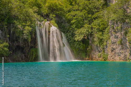 Long exposure waterfall during the day. green forest and rocky mountain. summer time at Plitvice Lakes in Croatia. crystal clear blue water © Marius Igas