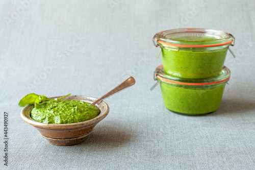 Fresh homemade arugula green pesto dip in glass jars. Vegan diet.