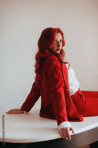 Gorgeous woman  in an elegant red suit with red hair . Natural female beauty.