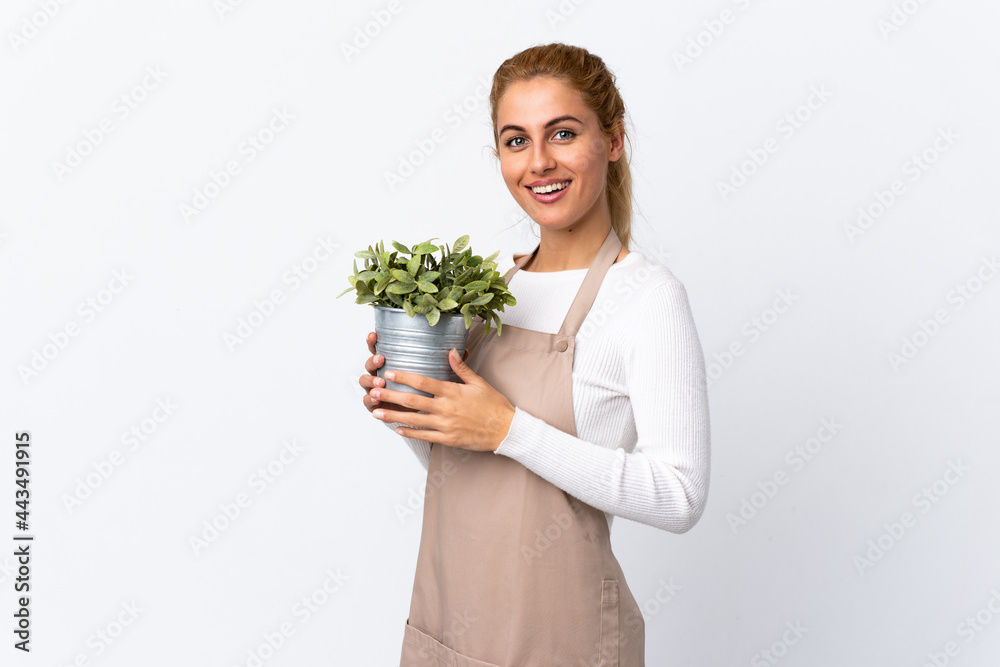 Young blonde gardener woman girl holding a plant over isolated white background applauding Young blonde gardener woman girl holding a plant over isolated white background applauding