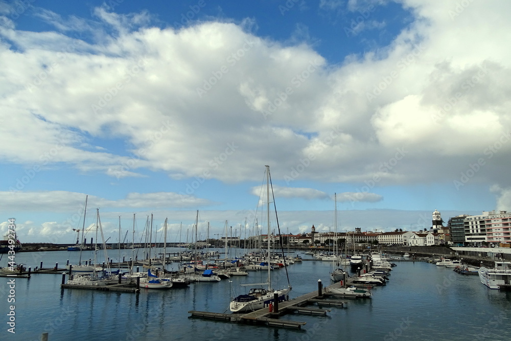 City Ponta Delgada, harbor with sailing boats, blue ocean and sky.