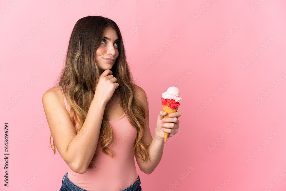 Young caucasian woman with a cornet ice cream isolated on pink background and looking up Young caucasian woman with a cornet ice cream isolated on pink background and looking up