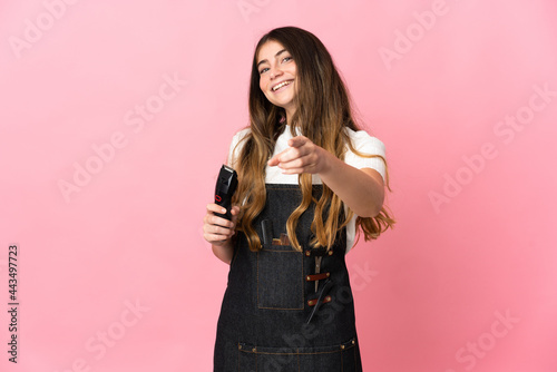 Young hairdresser woman isolated on pink background pointing front with happy expression