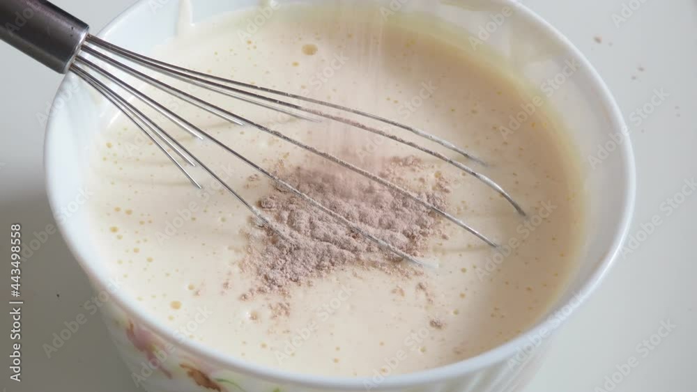 The girl prepares a cake at home. Whisk cream, eggs or whites, add cocoa. Makes chocolate dough. Cooking at home. Tasty food The girl prepares a cake at home. Whisk cream, eggs or whites, add cocoa. Makes chocolate dough. Cooking at home. Tasty food