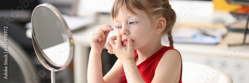 Valokuva Little girl paints her eyes and looks in mirror