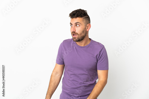 Caucasian man isolated on white background doing surprise gesture while looking to the side