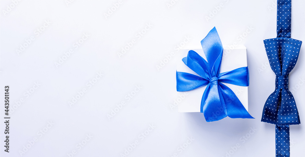 Gift father day. Blue bowtie or tie, white box with bow ribbon on light background. Happy loving family and Fathers Day concept. Gift father day. Blue bowtie or tie, white box with bow ribbon on light background. Happy loving family and Fathers Day concept.