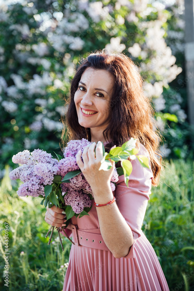 portrait of a beautiful brunette woman in a lilac dress with lilac flowers portrait of a beautiful brunette woman in a lilac dress with lilac flowers