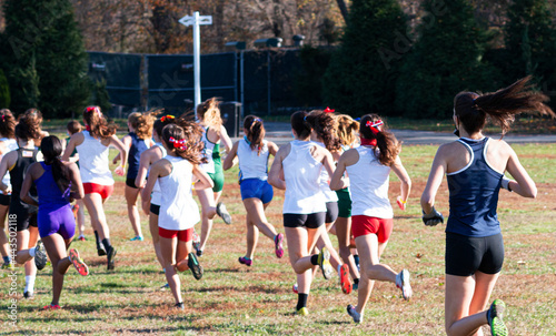High school cross country runners running across a field
