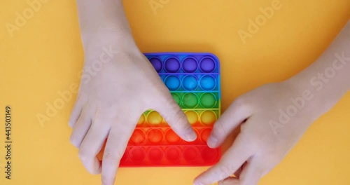 Child is playing trendy popular board game anti-stress toy pop it. Multi-colored popular silicone anti-stress toy pop it.