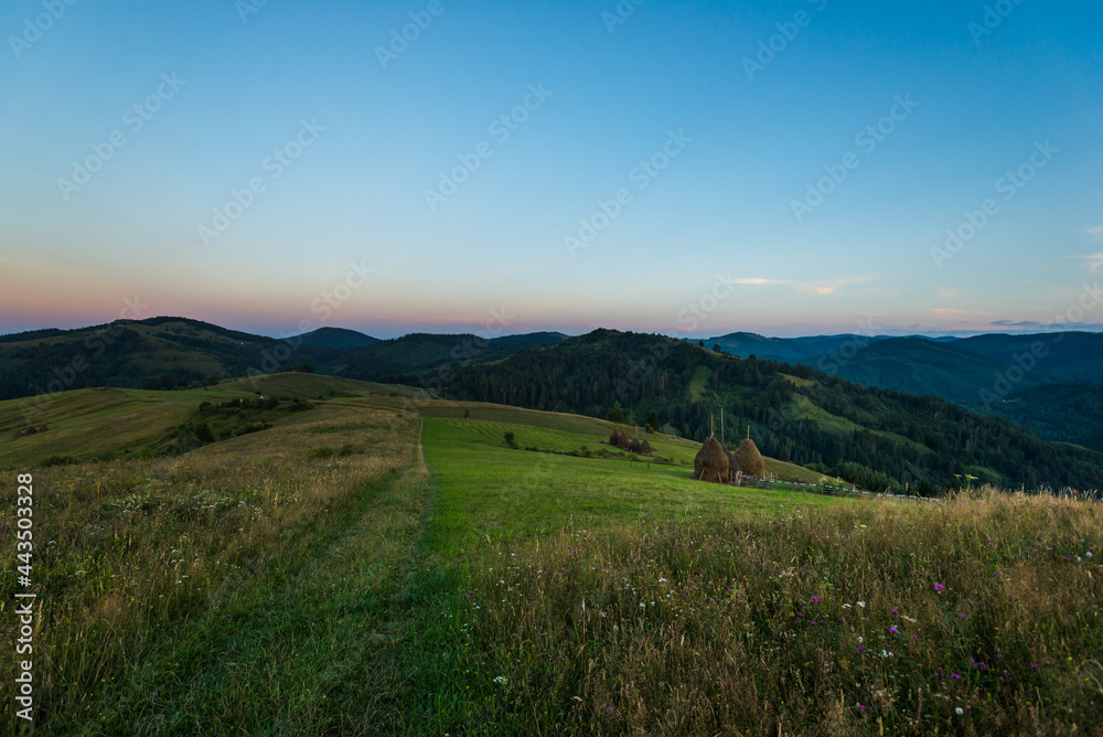 Country evening landscape with meadow and haycock