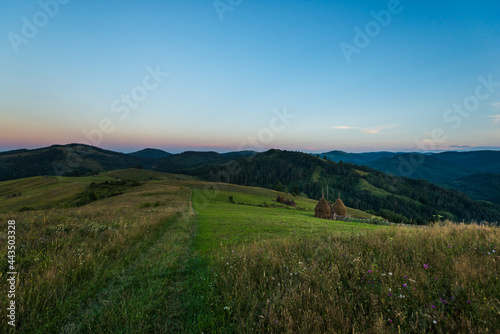 Country evening landscape with meadow and haycock