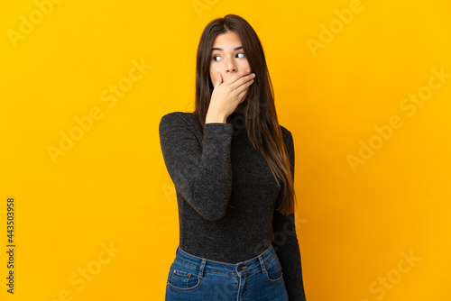 Teenager Brazilian girl isolated on yellow background doing surprise gesture while looking to the side