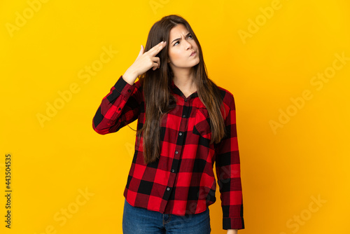 Teenager Brazilian girl isolated on yellow background with problems making suicide gesture © luismolinero