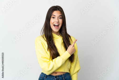 Teenager Brazilian girl isolated on white background surprised and pointing side