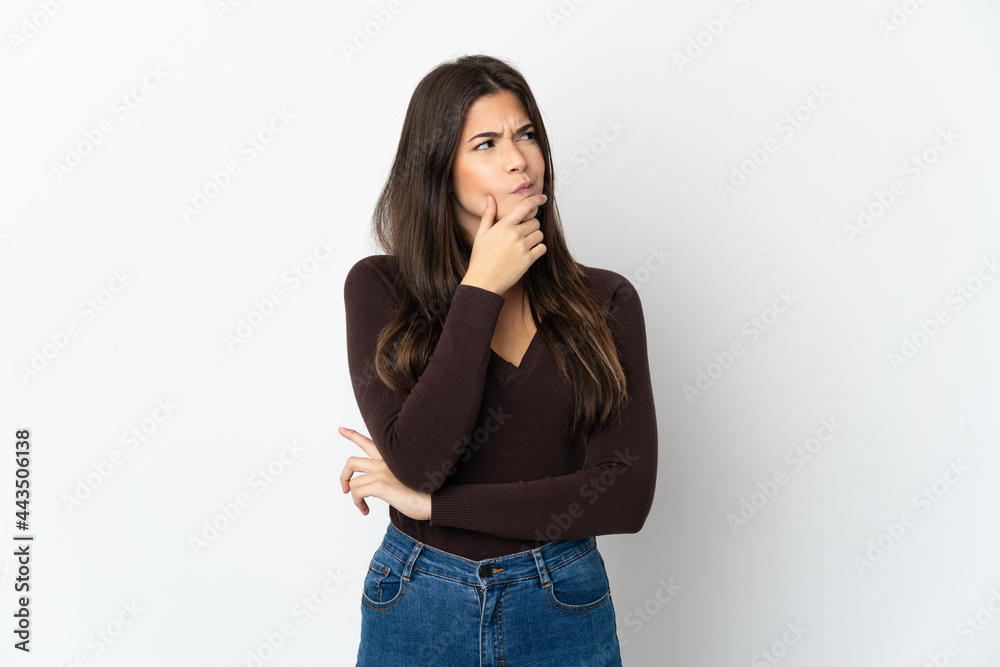 Teenager Brazilian girl isolated on white background having doubts and with confuse face expression Teenager Brazilian girl isolated on white background having doubts and with confuse face expression