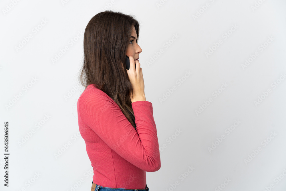 Teenager Brazilian girl isolated on white background keeping a conversation with the mobile phone with someone Teenager Brazilian girl isolated on white background keeping a conversation with the mobile phone with someone