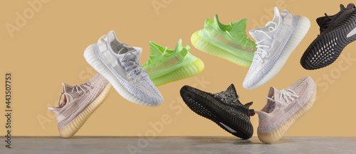 Flying sneakers isolated on a yellow background, different kind. Fashionable stylish sports casual shoes. Creative minimalistic mockup with shoes. Space for text. Shoe Store Advertising