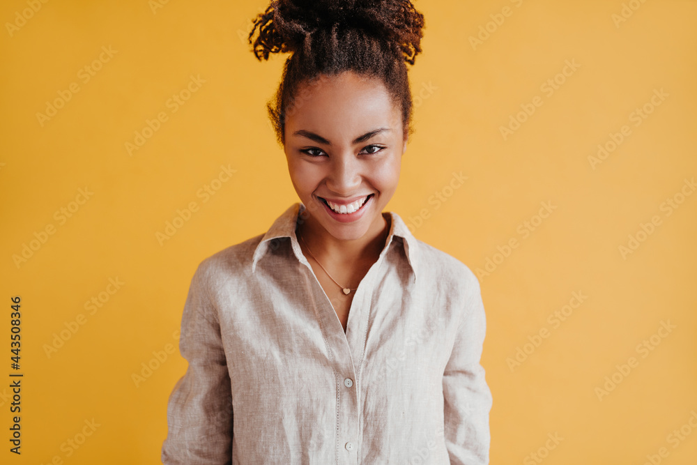 Front view of spectacular black woman laughing at camera. Studio shot of appealing african american girl isolated on yellow background. Front view of spectacular black woman laughing at camera. Studio shot of appealing african american girl isolated on yellow background.