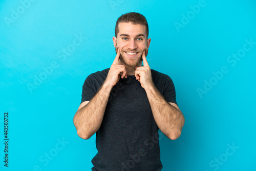 Young handsome caucasian man isolated on blue background smiling with a happy and pleasant expression