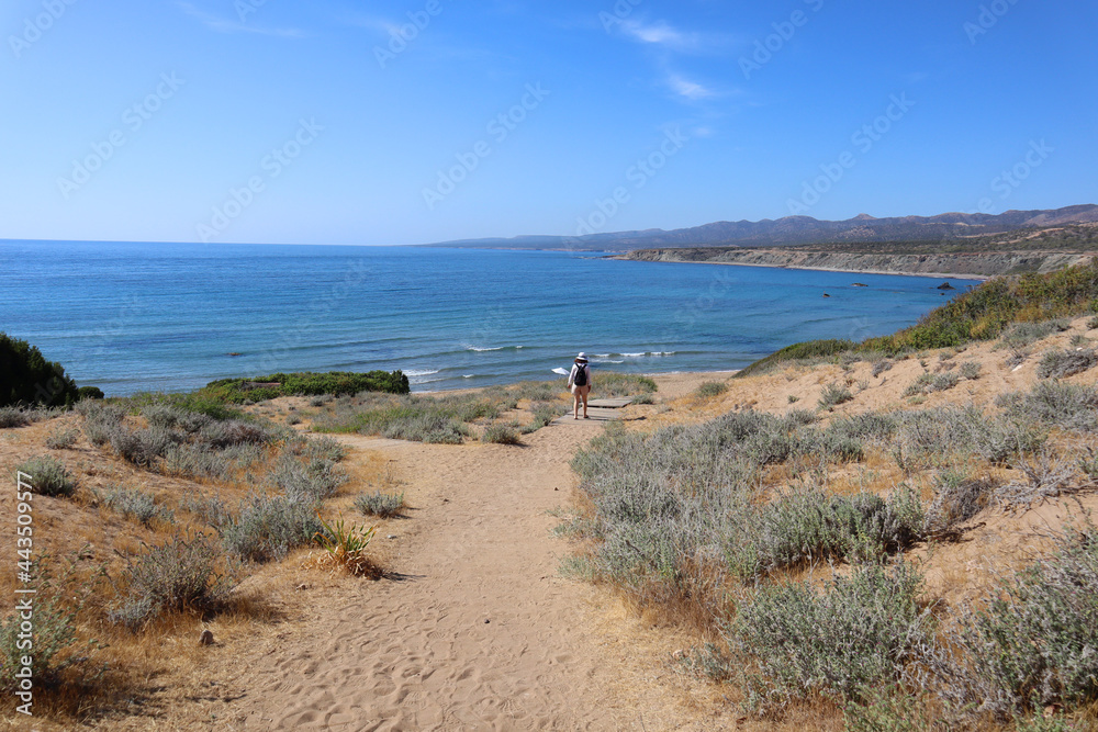Brunette Caucasian woman walking on an empty, sunny and isolated beach on the west coast of Cyprus by the Mediterranean sea Brunette Caucasian woman walking on an empty, sunny and isolated beach on the west coast of Cyprus by the Mediterranean sea