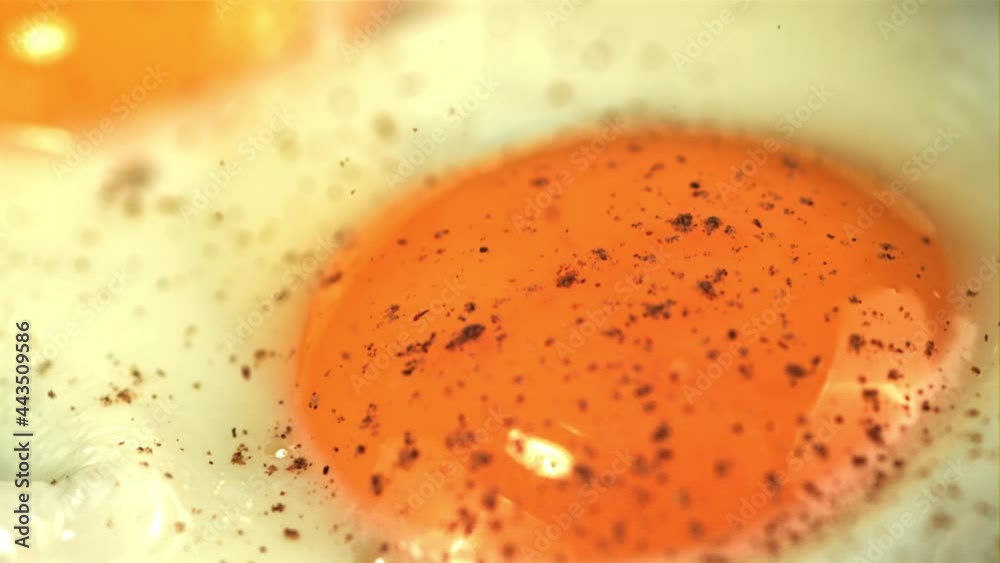 Super slow motion ground pepper falls on the fried egg. Macro background. Filmed on a high-speed camera at 1000 fps. Super slow motion ground pepper falls on the fried egg. Macro background. Filmed on a high-speed camera at 1000 fps.