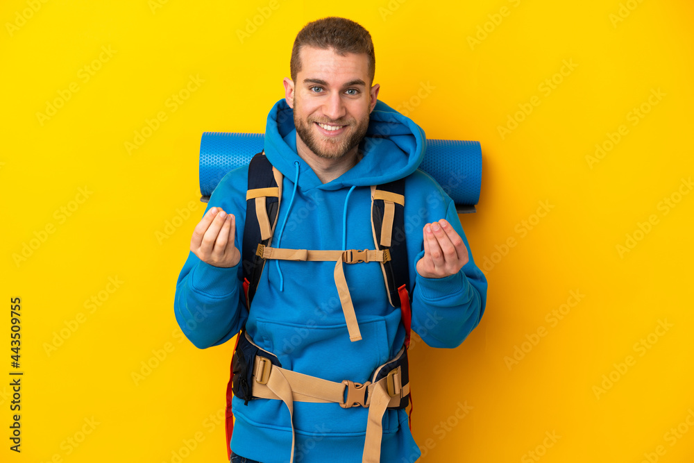 Young caucasian mountaineer man with a big backpack isolated on yellow background making money gesture Young caucasian mountaineer man with a big backpack isolated on yellow background making money gesture