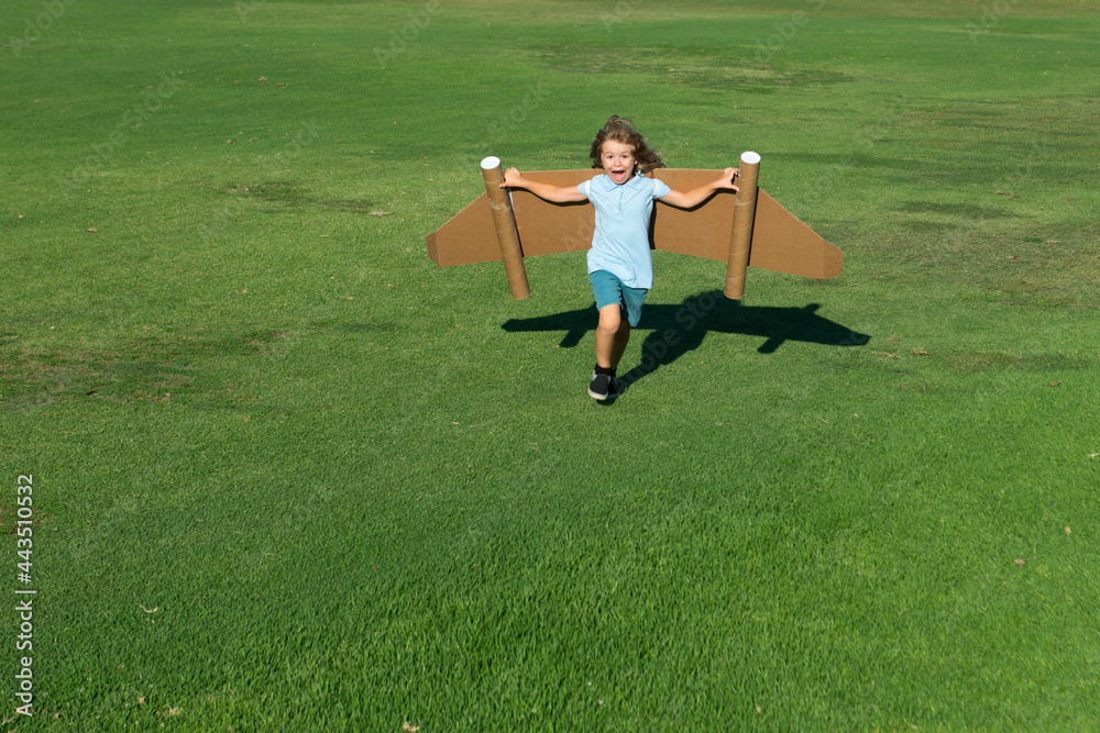 Fototapeta premium Kid imagination, child pilot with paper wings having fun at outdoor. Summer vacation and travel concept.
