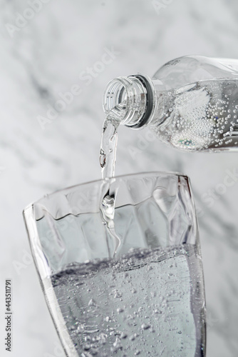 Canvas Print Clear drinking carbonated water is poured into glass on light background