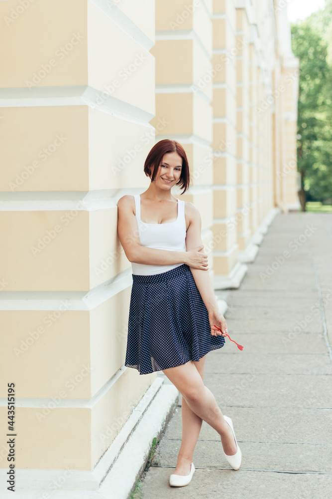 Happy caucasian red-haired girl in full growth walks in the city with a heart in her hands Happy caucasian red-haired girl in full growth walks in the city with a heart in her hands