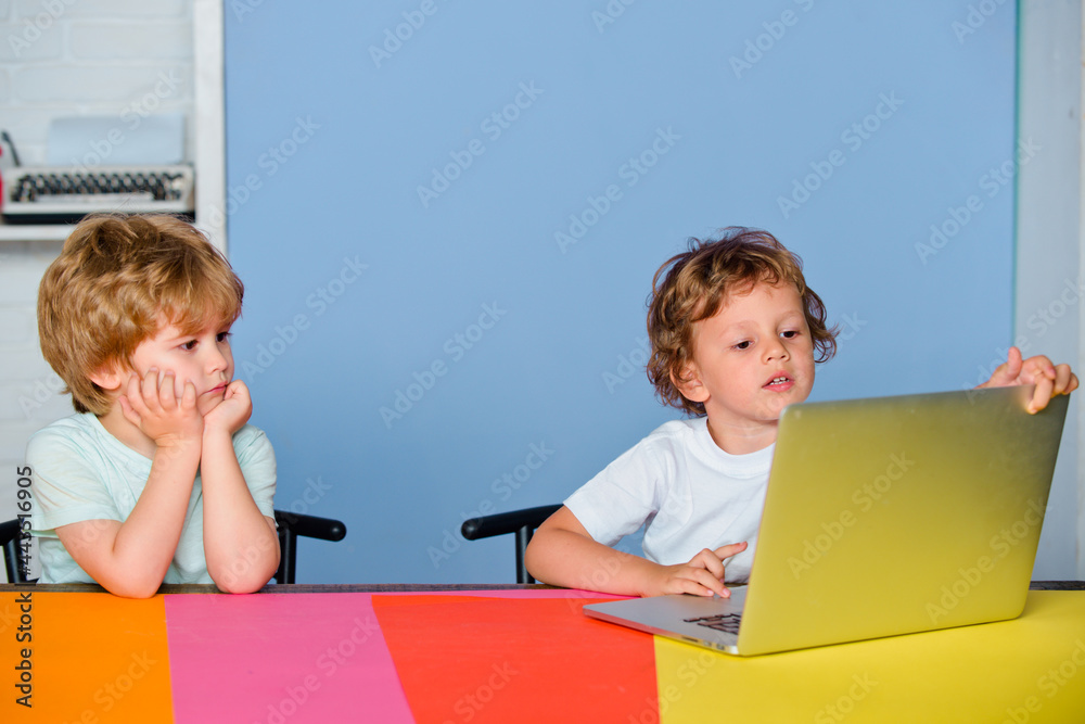 Little boys pupils with happy face expression near laptop, school concept. Kids with a notebook. Portrait of clever child boy pupil with laptop. Child from elementary school. Little boys pupils with happy face expression near laptop, school concept. Kids with a notebook. Portrait of clever child boy pupil with laptop. Child from elementary school.