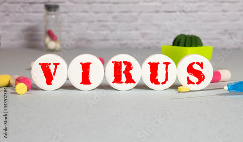 The word VIRUS on wooden blocks on the table. Medical concept with pills