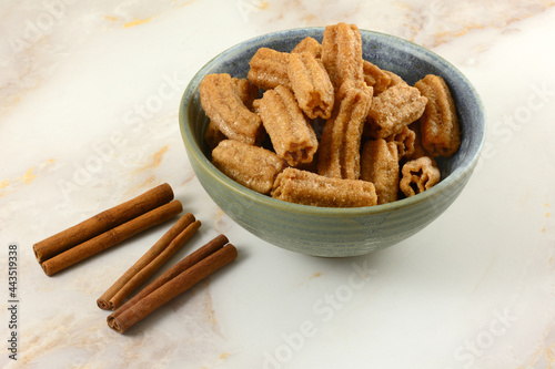 Cinnamon sugar churro snack in ceramic snack bowl with cinnamon sticks on table