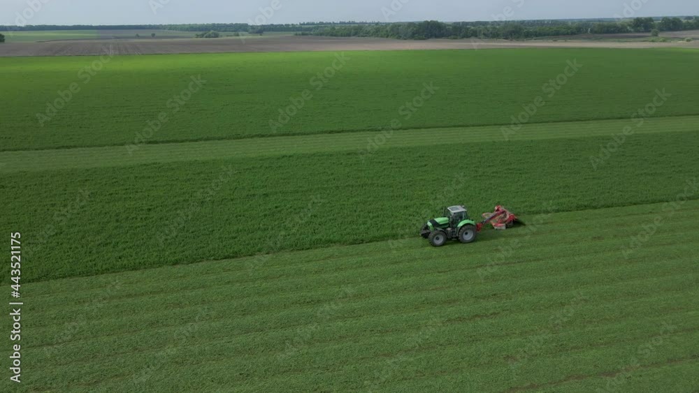 Mowing with a agriculture machine, modern tractor with mowers on the big farm field Mowing with a agriculture machine, modern tractor with mowers on the big farm field