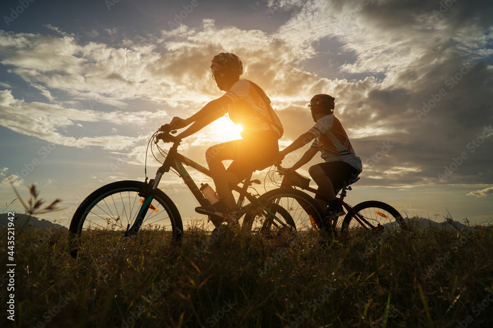 Young Couple in love fun and happy riding mountain bike after covid-19 coronavirus outbreak. End of the coronavirus outbreak. Silhouette cycling man and woman riding mountain bike at sunset time. Young Couple in love fun and happy riding mountain bike after covid-19 coronavirus outbreak. End of the coronavirus outbreak. Silhouette cycling man and woman riding mountain bike at sunset time.