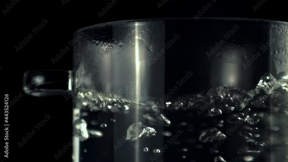 Super slow motion in a transparent pan boils water with air bubbles. On a black background. Filmed on a high-speed camera at 1000 fps. Super slow motion in a transparent pan boils water with air bubbles. On a black background. Filmed on a high-speed camera at 1000 fps.