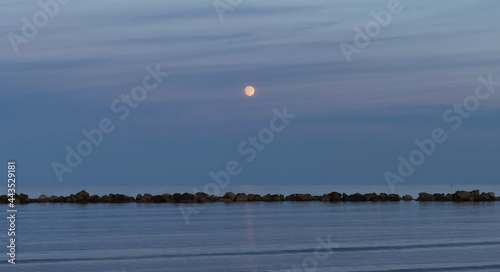 Luna sul mare sopra gli scogli al tramonto