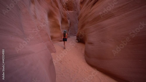 Back of female walking on sand in a narrow slot canyon passage. Antelope Canyon, Arizona USA, slow motion photo