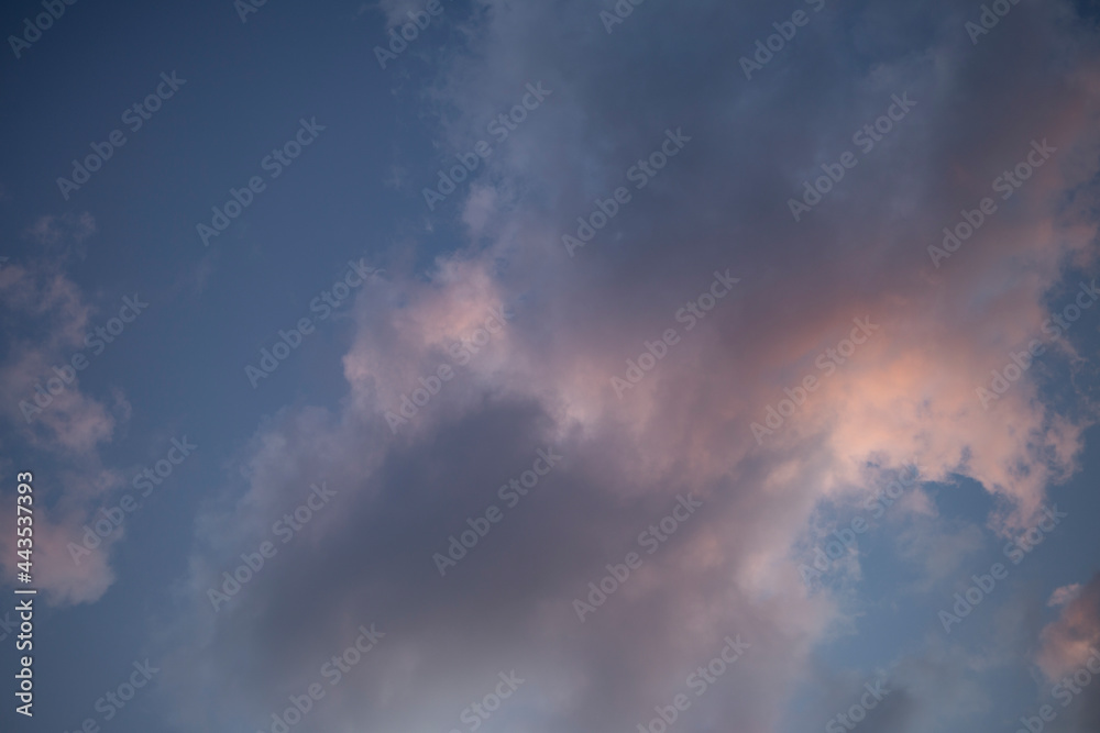 Blue sky with gray and pink puffy clouds