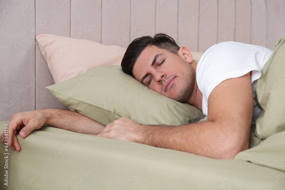 Man sleeping in comfortable bed with green linens Man sleeping in comfortable bed with green linens