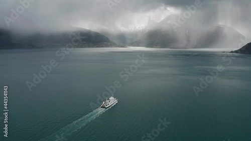 Aerial view of the ferry on the Afarnes-Solsnes route crossing the fjord. The dramatic view of the sea opens up as the ferry is moving towards the dark storm, the curtain of heavy rain looming ahead. photo