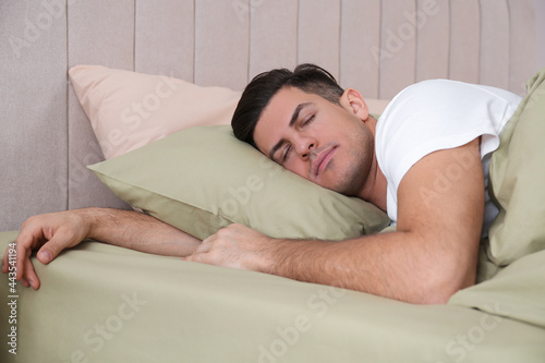 Man sleeping in comfortable bed with green linens
