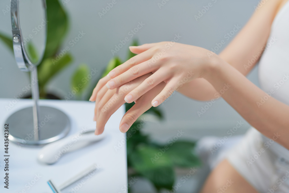 Attractive young woman applying hand cream at home