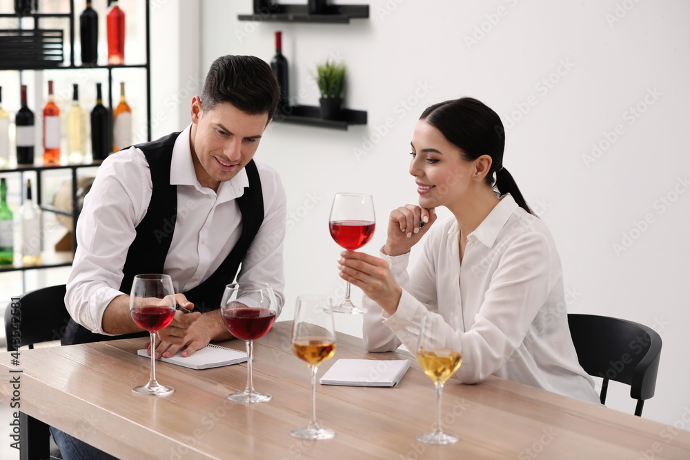 Sommeliers tasting different sorts of wine at table indoors