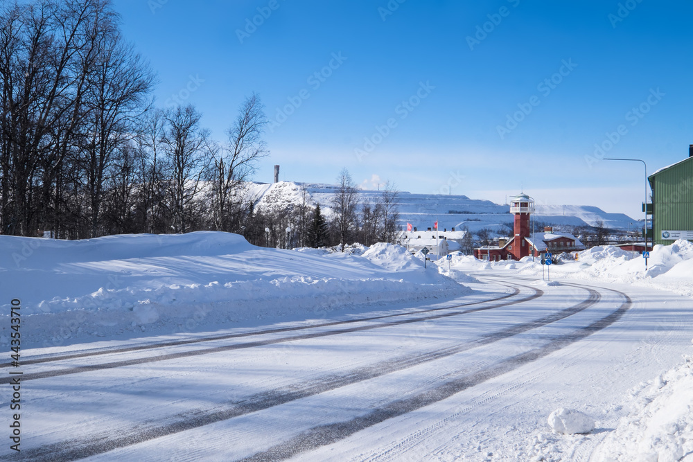KIRUNA, SWEDEN - MARCH 15 2020: The old firestation of Kiruna in winter, now used as a regional TV station.  In the background the factories of the LKAB, a large Swedish iron mining company