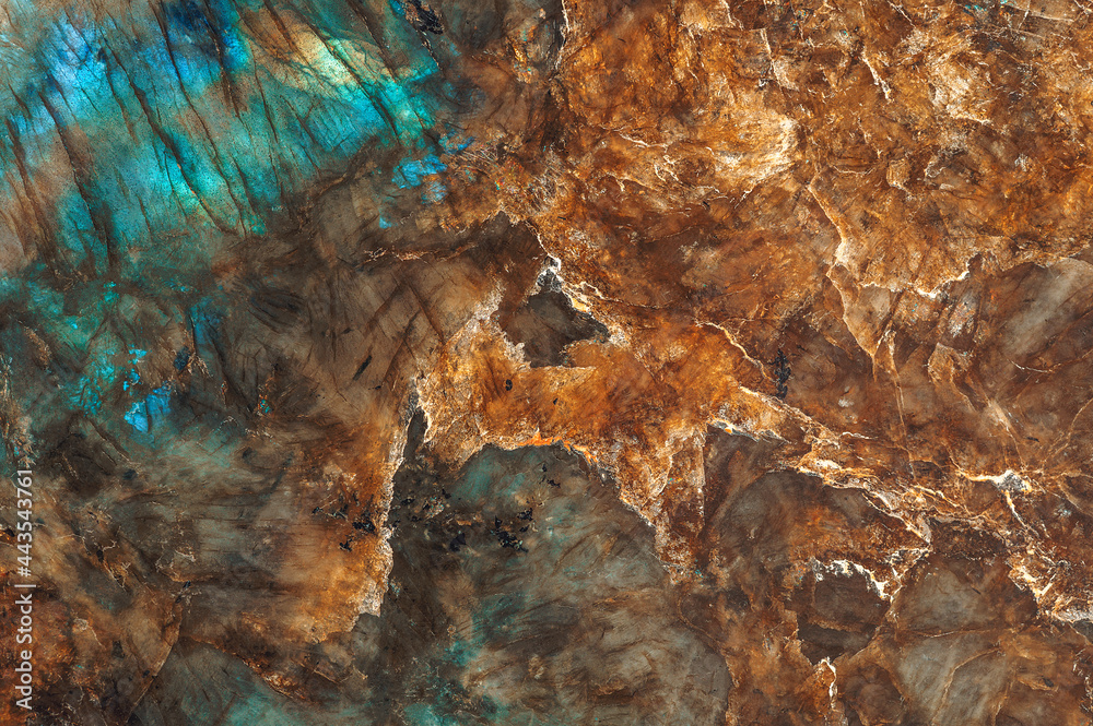 The texture of a mineral stone of labradorite or granite, shimmering with different colors, is close-up.